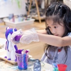 Girl pouring paint onto an art bear