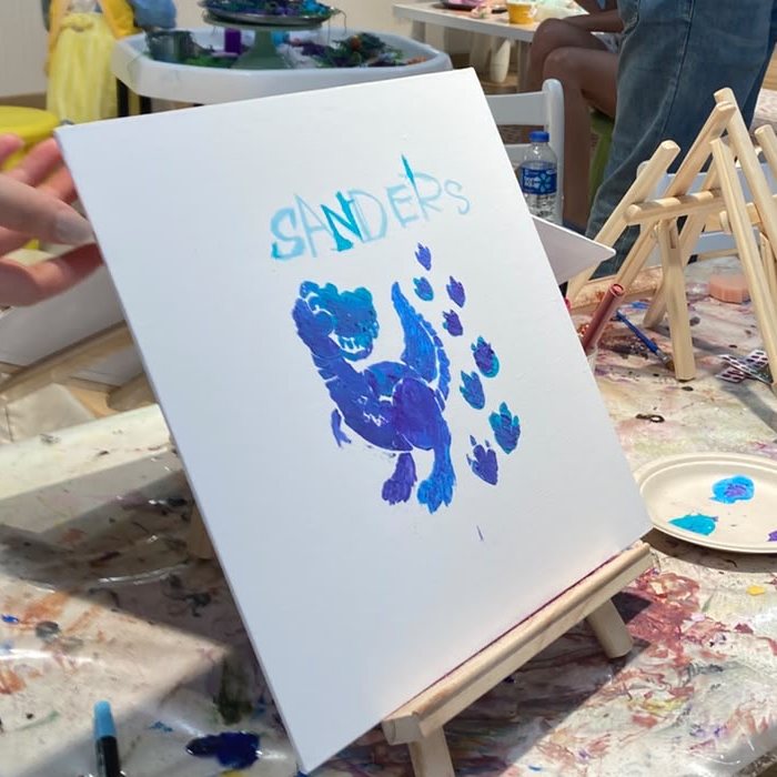 Kid's canvas painting of a blue dinosaur on a mini easel