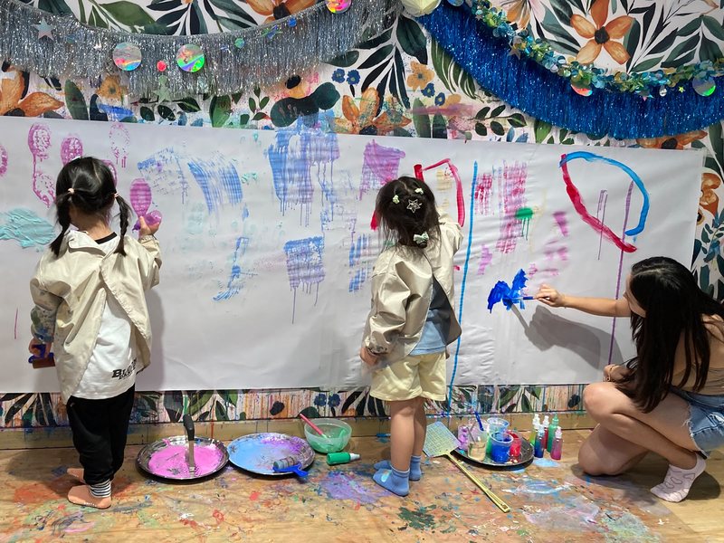 Kids painting a giant paper mural on the messy wall