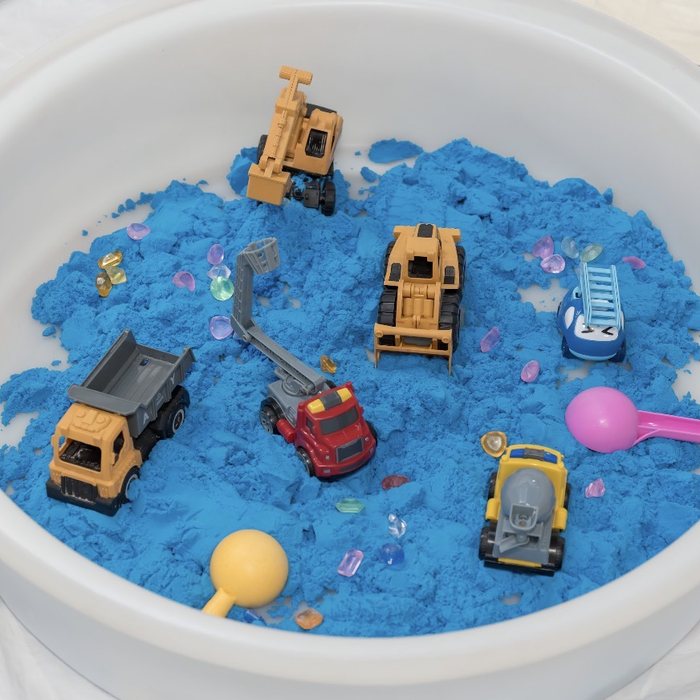Blue kinetic sand tub with toy diggers and gems